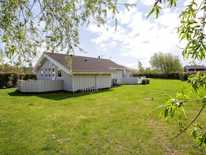 Une maison de plain-pied avec un toit en pente, une cour clôturée et un petit jardin.