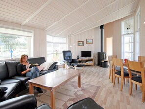 A spacious living room with a sofa, a coffee table, a TV, and a fireplace. - 4 Star Holiday Home in Rude (Bisserup)