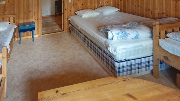 Una habitación de madera con literas, una mesita y un banco.