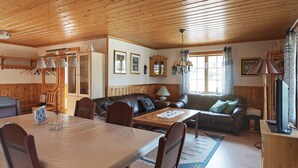 Una sala de estar acogedora con una mesa de comedor, sofá de cuero y techo de madera.