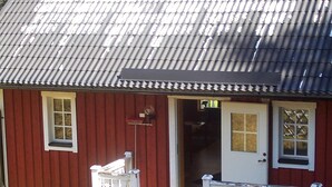 A red building with a white porch and a door. - 6 Person Holiday Home in Torsby (Torsby)