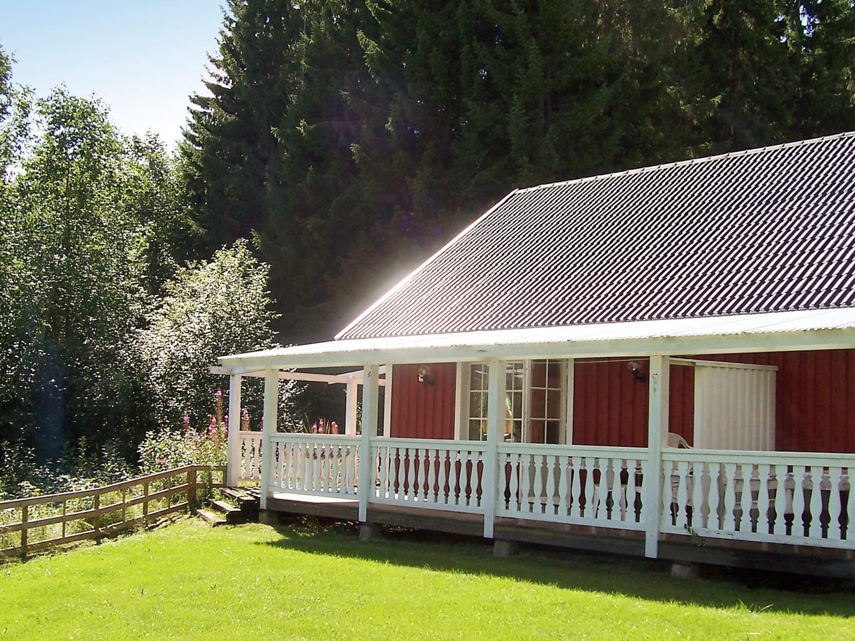 A red building with a white porch and a metal roof.