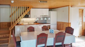 Un comedor con mesa y sillas, y una cocina con armarios blancos, microondas y refrigerador.