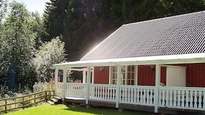 A red building with a white porch and a metal roof. - 6 Person Holiday Home in Torsby (Torsby)