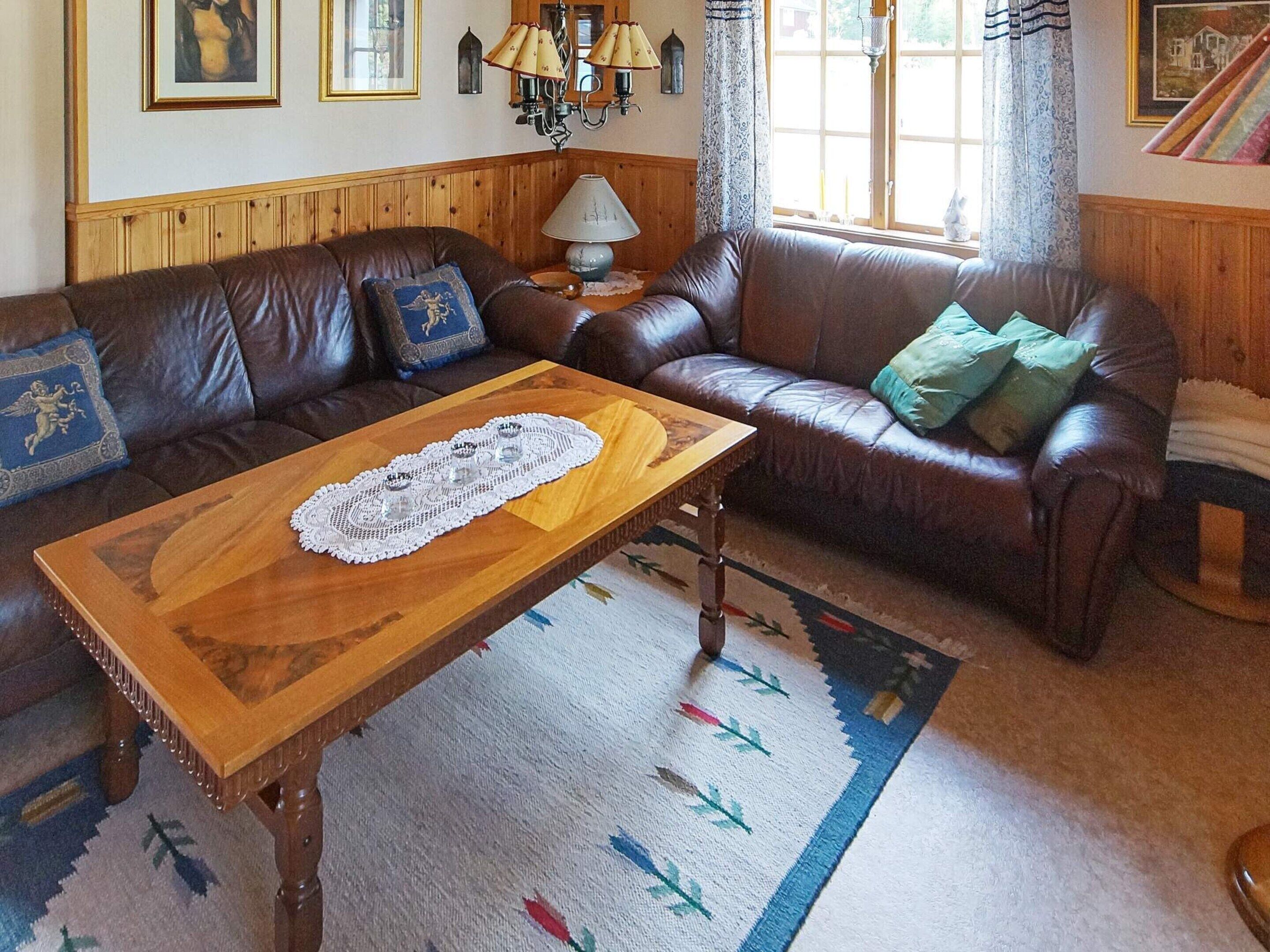 Una sala de estar con un sofá de cuero marrón, una mesa de centro de madera y un tapete estampado.