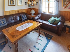 Una sala de estar con un sofá de cuero marrón, una mesa de centro de madera y un tapete estampado.
