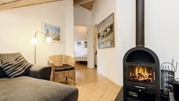 A cozy living room with a fireplace, a sofa, a chair, and a lamp.