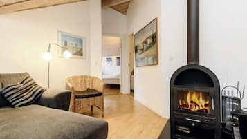 A cozy living room with a fireplace, a sofa, a chair, and a lamp.