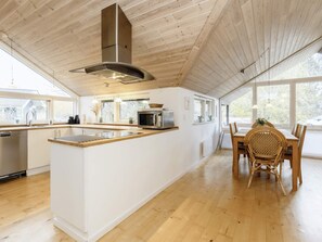 A modern kitchen with a central island, wooden ceiling, and large windows. - 8 Person Holiday Home in Rodby (Rodby)