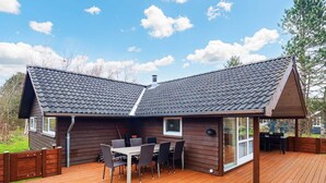 A wooden deck with a dining area and a covered outdoor space.