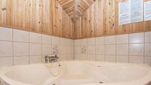 Ein Badezimmer mit einer großen Badewanne, Holzwandverkleidung und Fliesenboden.
