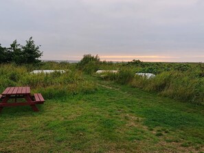 Una mesa de picnic en un área verde con vista al agua y el horizonte lejano.