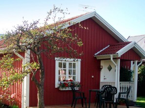 A red building with a white window and a small porch with chairs. - 4 Person Holiday Home in Bello (Hjältevad)