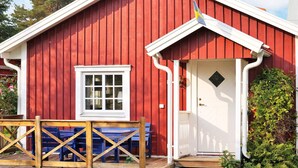 Un bâtiment en bois rouge avec une porte blanche, une fenêtre et un porche doté de bancs bleus.