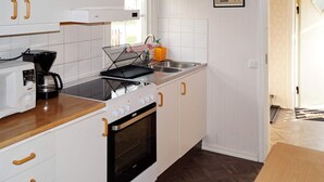 A modern kitchen with white cabinetry, a stove, a microwave, and a coffee maker. - 4 Person Holiday Home in Bello (Hjältevad)