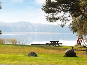 A picnic table and bench by a calm lake with a forest in the background. - 4 Person Holiday Home in Bello (Hjältevad)