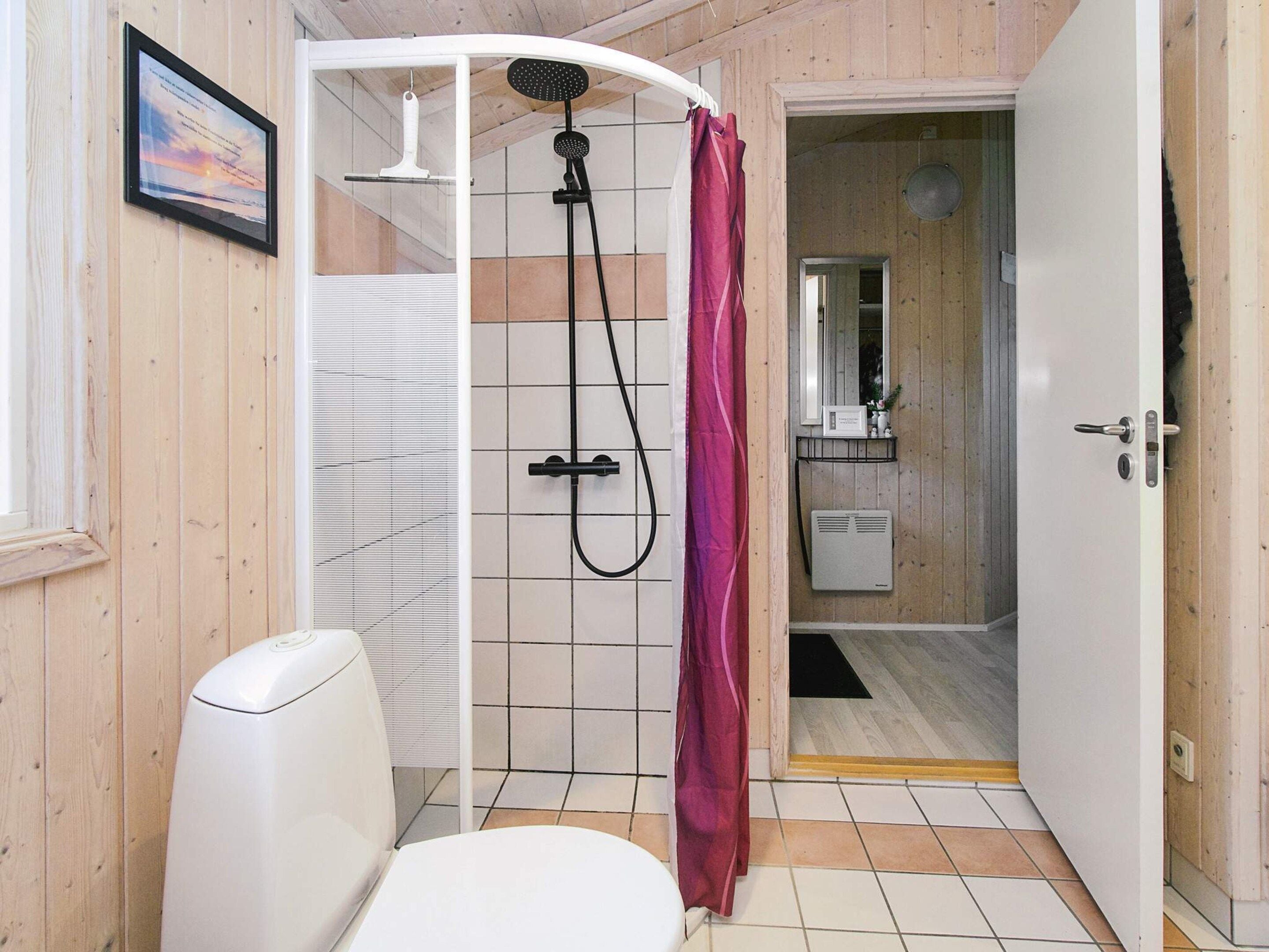 A bathroom with a shower, toilet, and a mirror.