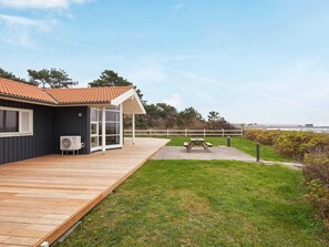 A coastal house with a wooden deck, a covered patio, and a picnic table.