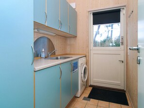 A compact kitchen with a washing machine, a sink, and a door with a window. - 5 Star Holiday Home in Gorlev (Gørlev)