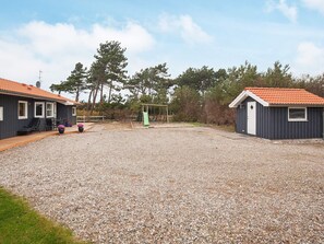 A residential area with two houses, a gravel driveway, and a swing set. - 5 Star Holiday Home in Gorlev (Gørlev)