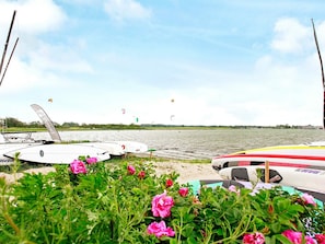 A lakeside view with boats and kites, surrounded by greenery and flowers. - Holiday Home in Gelting (Gelting)