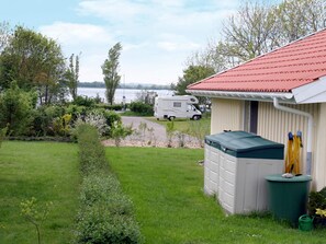 A caravan park with a grassy area, a small shed, and a body of water in the background.