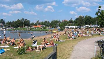Un parque junto al lago, con gente relajándose sobre el césped y cerca del agua.