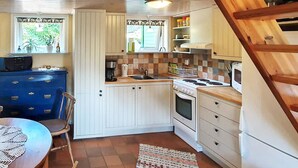 A compact kitchen with white cabinets, a blue dresser, a stove, and a sink.