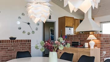 Un comedor moderno con una mesa redonda, un jarrón con flores y una lámpara de techo original.