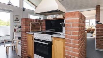 A compact kitchen with a built-in oven, a grill, and a brick wall design.