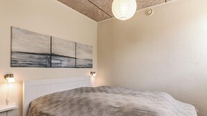 A bedroom with a bed, a nightstand, a wall-mounted lamp, and a ceiling light fixture.