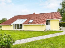 A two-story house with a red-tiled roof, a small porch, and a paved driveway.