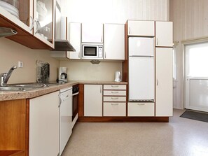 A compact kitchen with a microwave, refrigerator, sink, and a coffee maker. - Holiday Home in Otterndorf (Otterndorf)