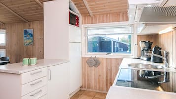 A compact kitchen with white cabinets, a window, and a stainless steel sink.