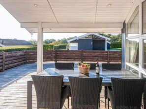 An outdoor patio with a table and chairs, a bottle of wine, and a basket of flowers.