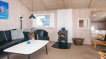 Una habitación acogedora con sofá, mesa, sillón, chimenea y cama.
