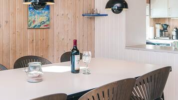 A dining area with a table, chairs, a wine bottle, and glasses.