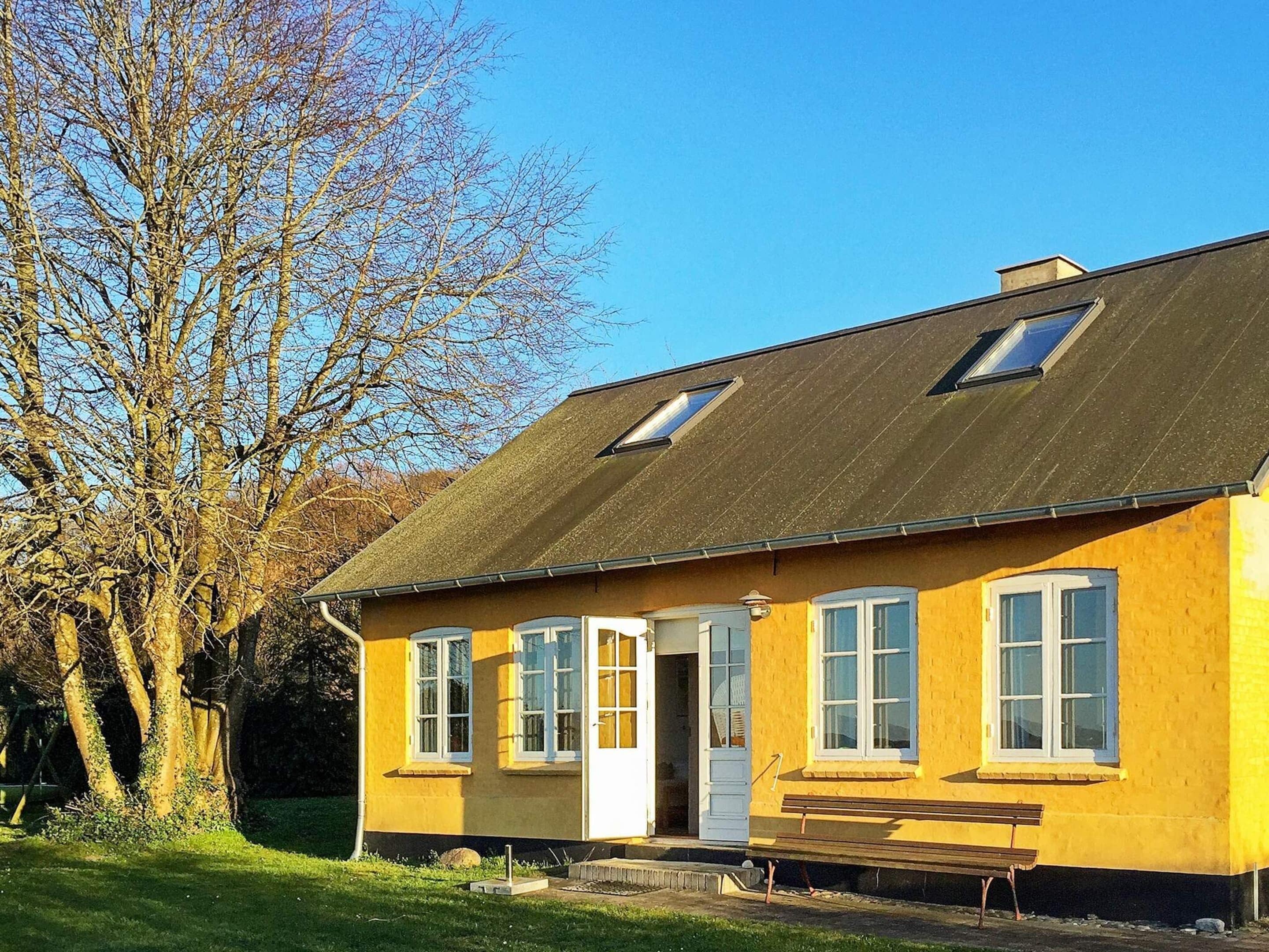 A yellow building with a sloped roof, a door, and windows.