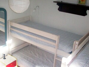 Een stapelbed met een klein nachtkastje en een wandlamp.