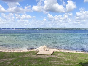 A beach with a wooden platform and a grassy area. - 6 Person Holiday Home in Aabenraa (Aabenraa)