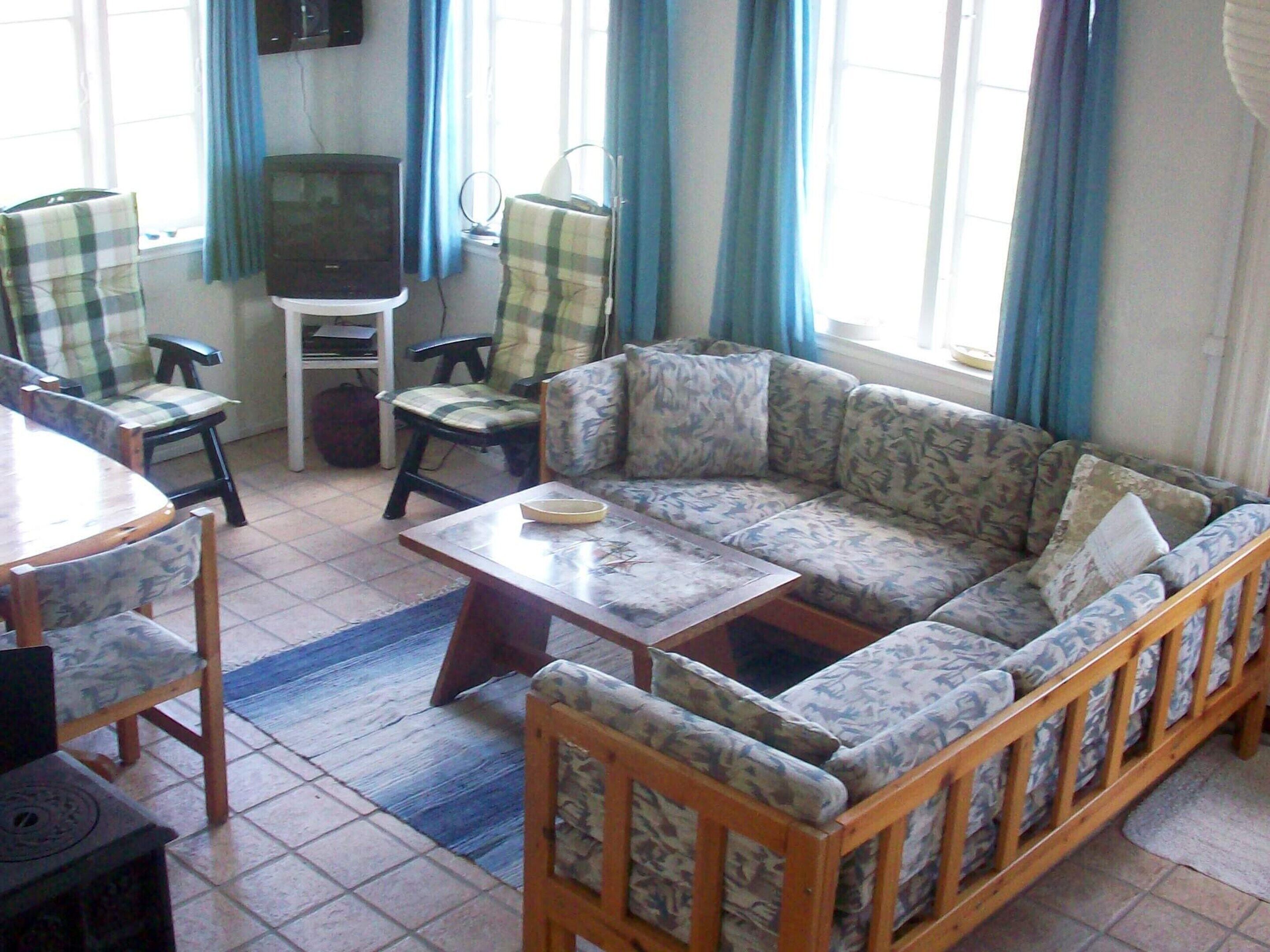 Una sala de estar con sofá, sillas, una mesa de centro y un televisor.