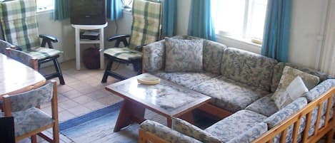 A living room with a sofa, chairs, a coffee table, and a television.