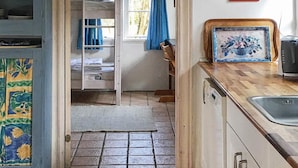 A kitchen with a tiled floor, a sink, a wooden countertop, and a door leading to a bedroom with a bunk bed. - 6 Person Holiday Home in Aabenraa (Aabenraa)