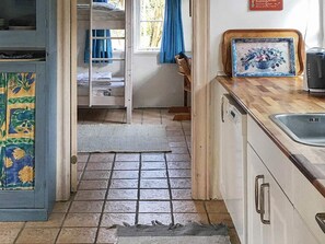 A kitchen with a tiled floor, a sink, a wooden countertop, and a door leading to a bedroom with a bunk bed. - 6 Person Holiday Home in Aabenraa (Aabenraa)