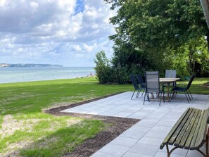 A patio with a table and chairs, a bench, and a view of the sea. - 6 Person Holiday Home in Aabenraa (Aabenraa)
