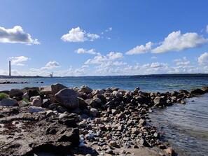 A rocky shoreline with a clear sky and distant cityscape. - 6 Person Holiday Home in Aabenraa (Aabenraa)
