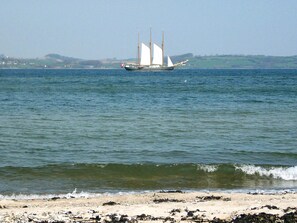 A sailboat on a calm sea with a sandy beach in the foreground. - 6 Person Holiday Home in Aabenraa (Aabenraa)