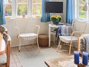 A room with a television, two chairs, a small table with a plant, and a window with curtains. - 6 Person Holiday Home in Aabenraa (Aabenraa)