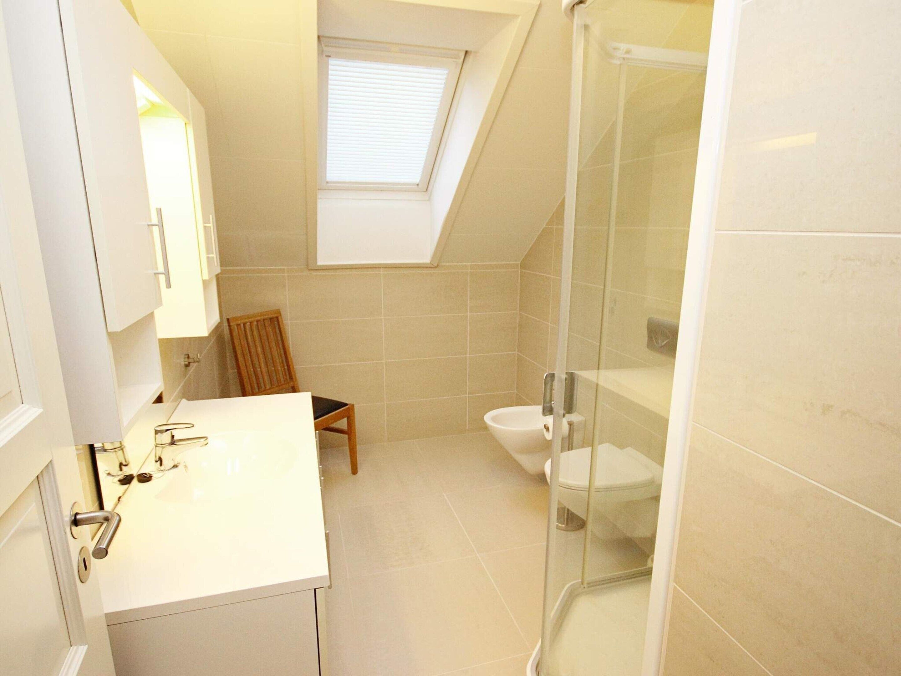 Et moderne badeværelse med ovenlys, brusekabine og toilet.