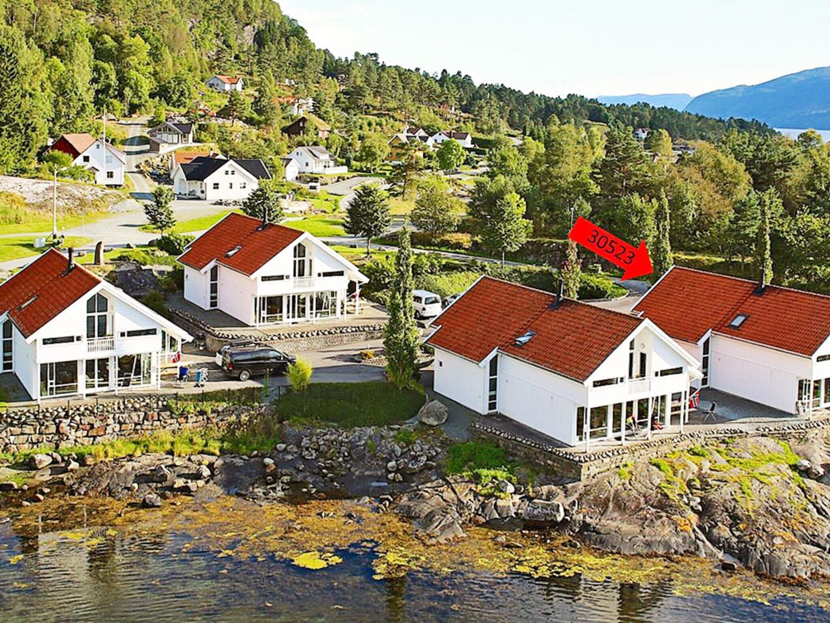 Et kystnære boligområde med hvide huse, en stenvæg og et vandareal med alger.